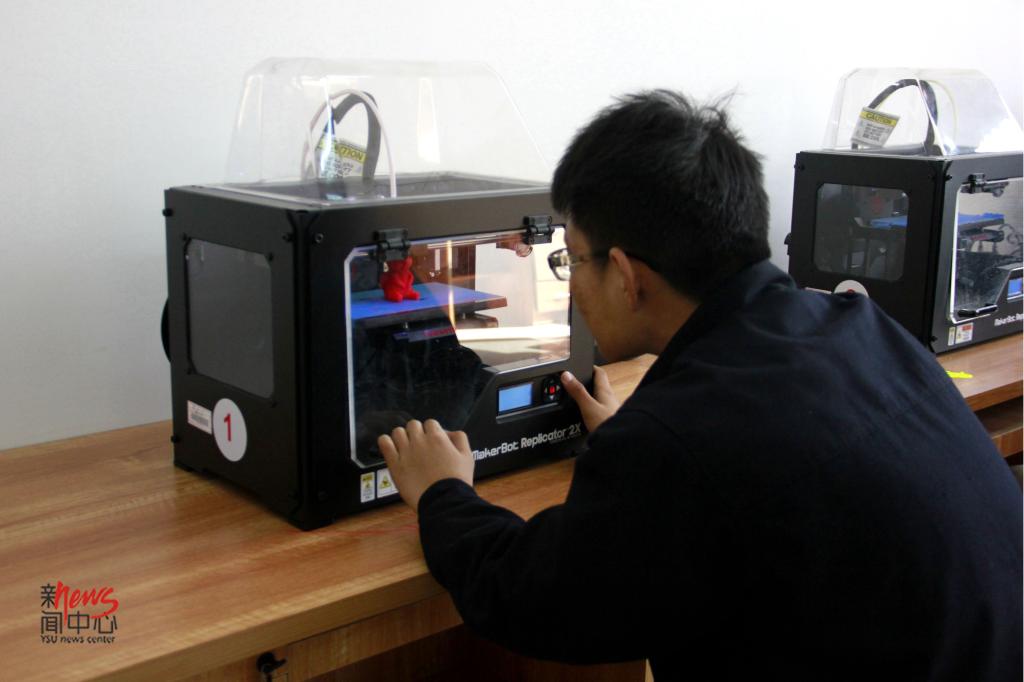这是学校今年新引入的3D立体打印机,他没想到自己这么幸运可以操作如此高端大气上档次的设备,看里面的小玩偶已经打印出来一大半了。(毕佳畅 摄)