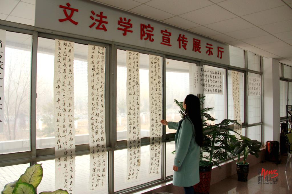人文馆里的宣传展示厅新挂上了很多书法作品,她很羡慕能写出这些好字的老师同学。(李晖 摄)